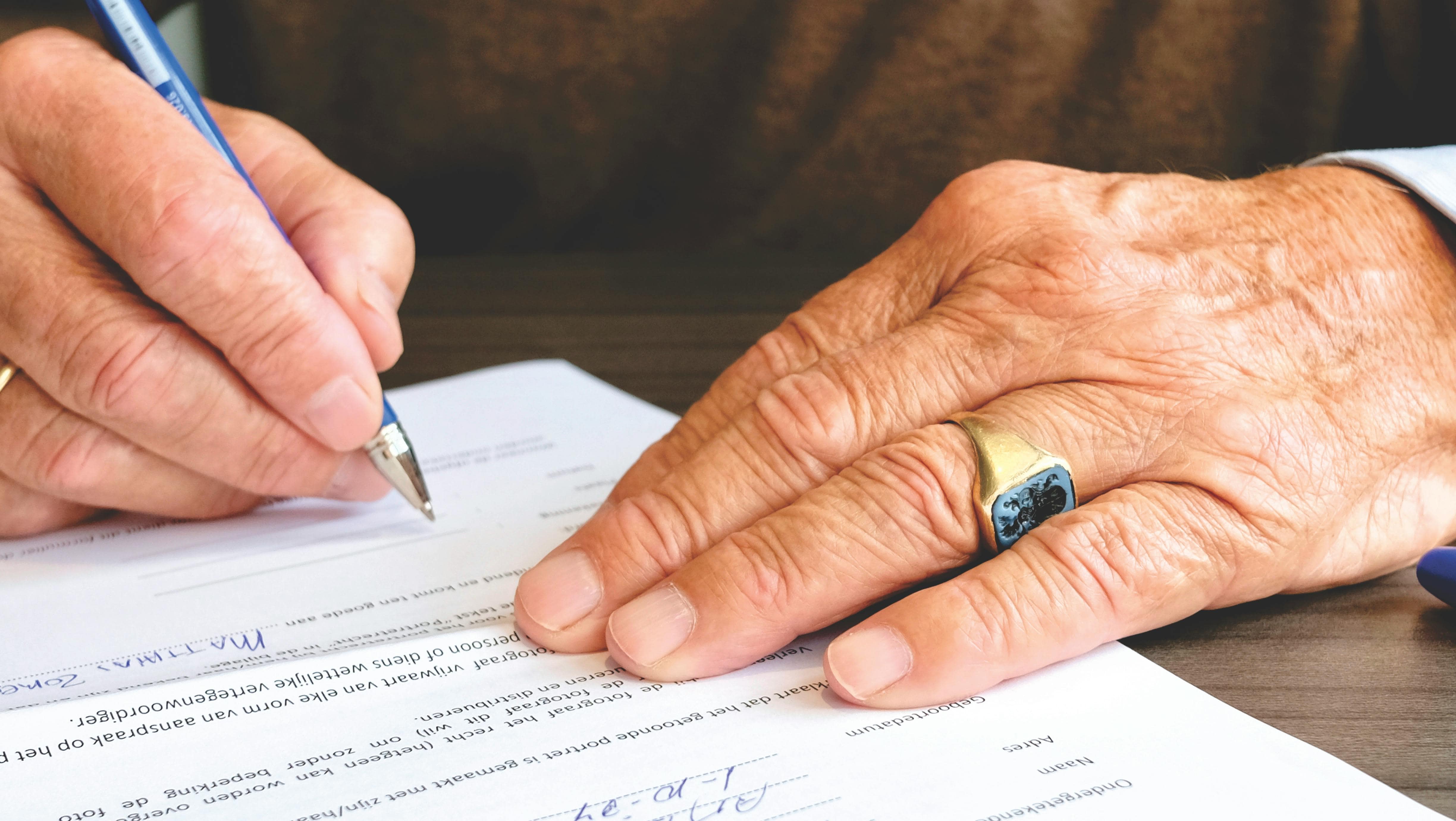 Close-up of a hand signing a document with a pen